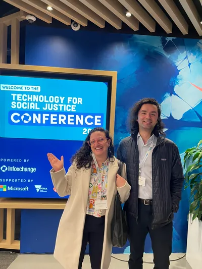 Carol and I in front of a sign at the Technology for Social Justice Conference 2024